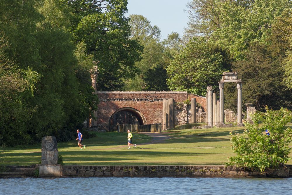 Joggers pass the Leptis Magna ruins at Virginia Water, Windsor Great Park